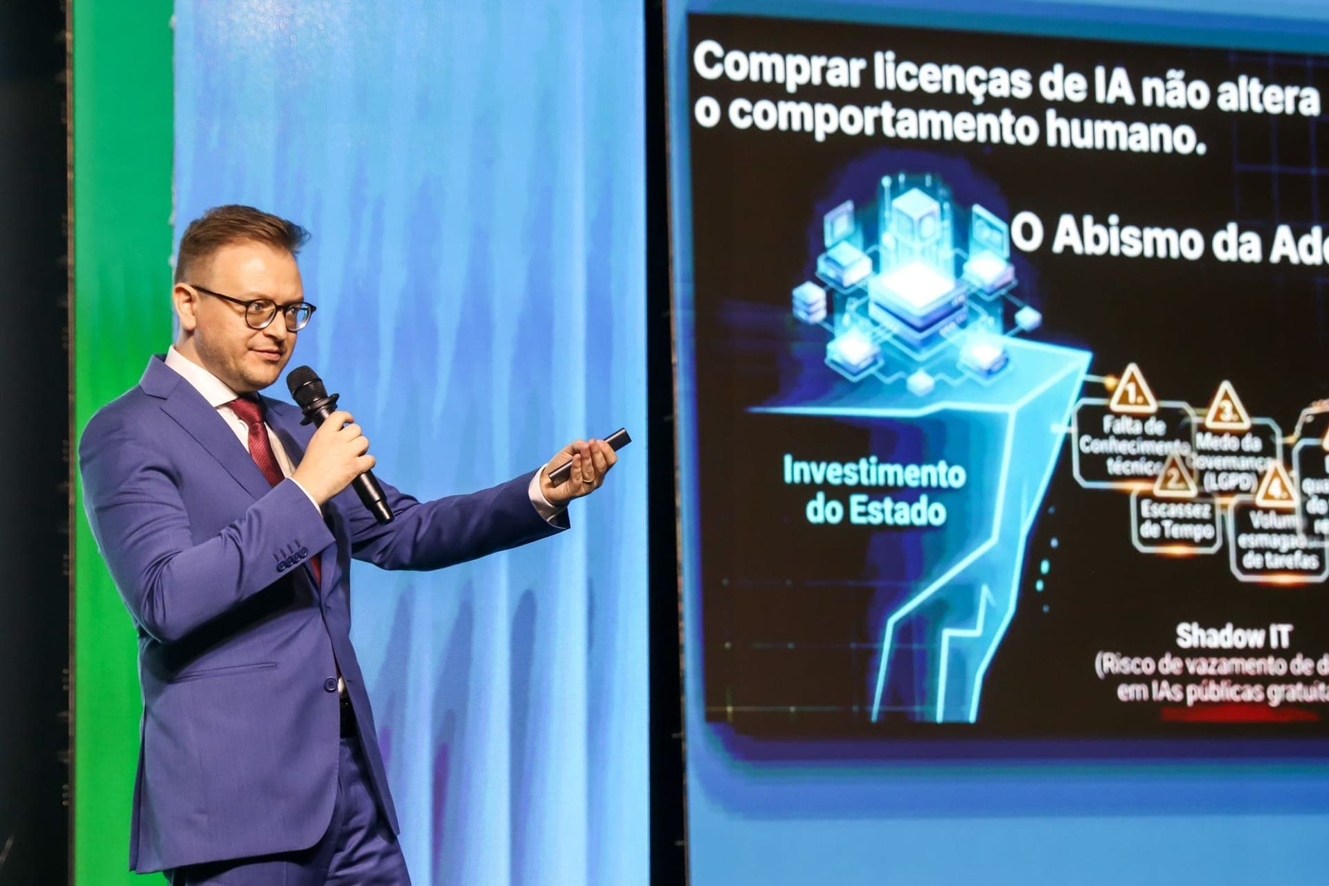 Ivan Mayer Caron sozinho no palco do ENASTIC, apontando para o telão com a tese da palestra